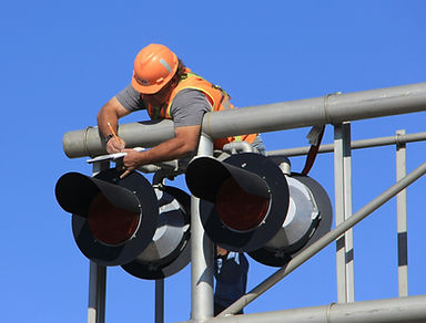 Man leaning over metal framework conducting maintenance on traffic lights