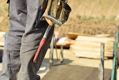 Close up of a construction worker with a tool belt. A hammer is hanging down from the belt.